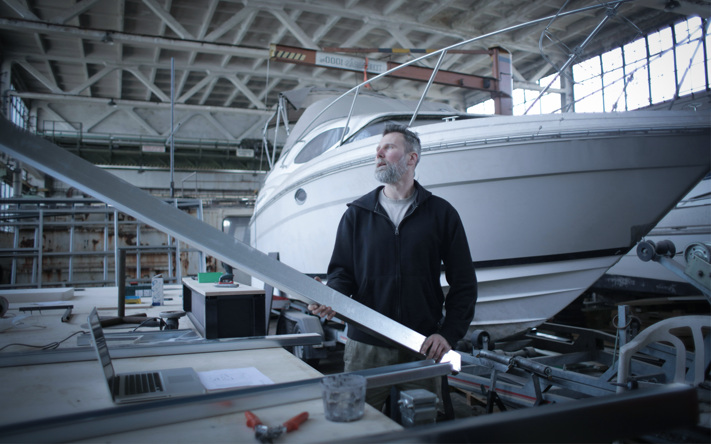 Homme tenant une pièce métallique près d'un bateau Découpe au laser pour les amateurs